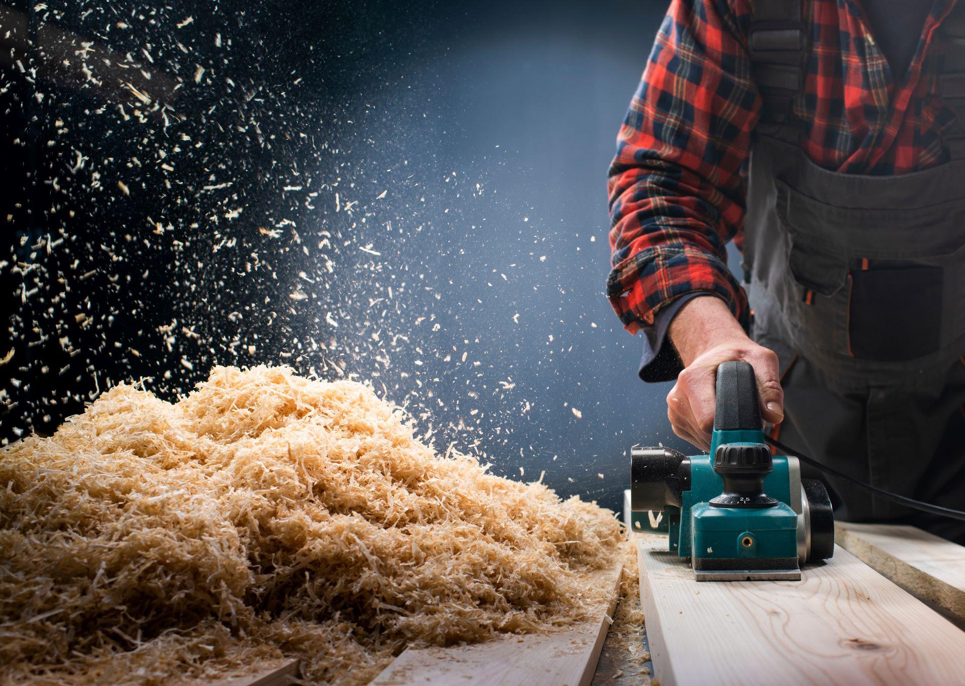 Arbeiter schleift Holz mit entstehendem Holzstaub